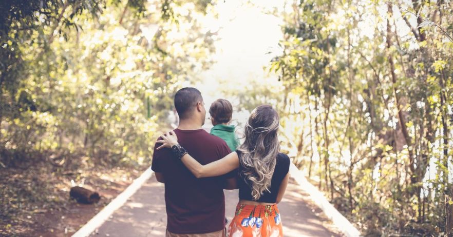 Family walking through a public park carrying their child.