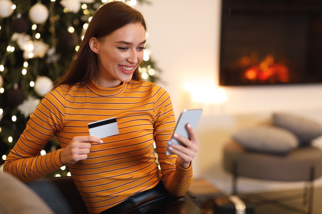 Customer tapping a debit card at a gift shop checkout while holiday lights glow in the background. (prompt and alt text recommendation)